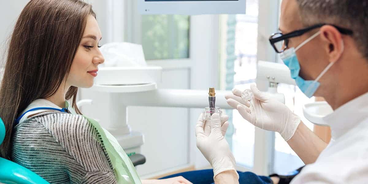 Dentist discussing a dental implant with a patient during an in-office consultation using dental equipment