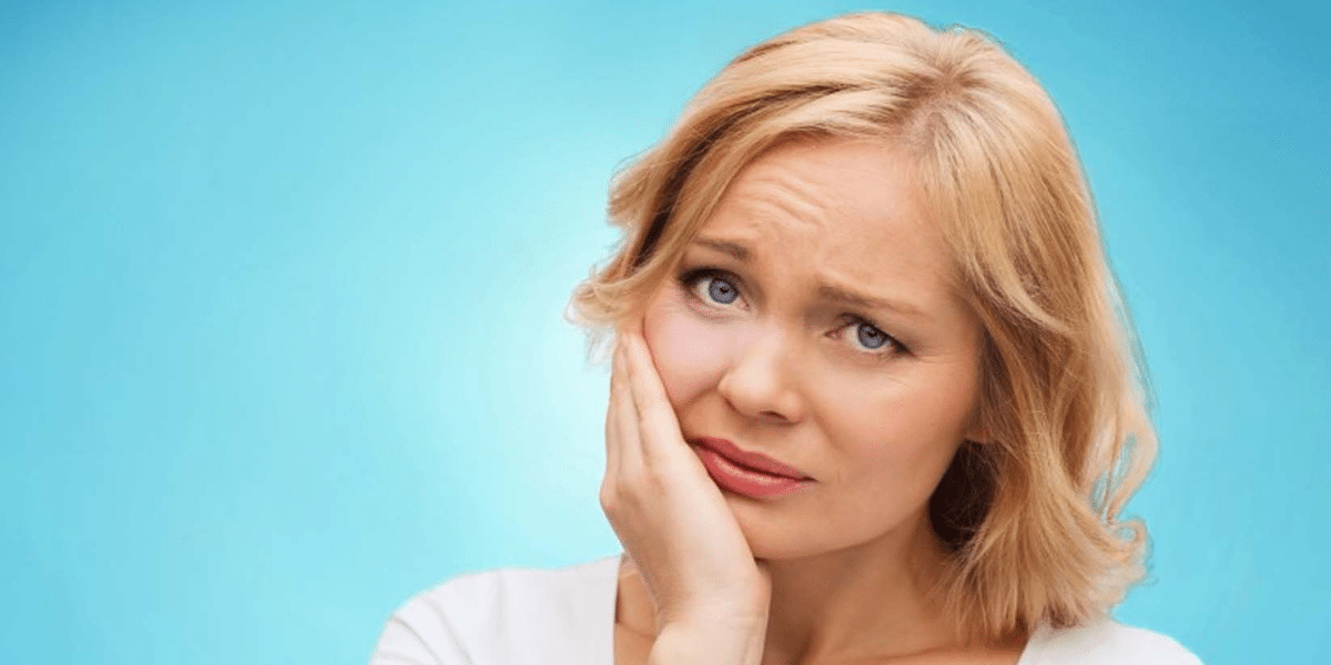Woman holding her cheek with a concerned expression suggesting dental pain