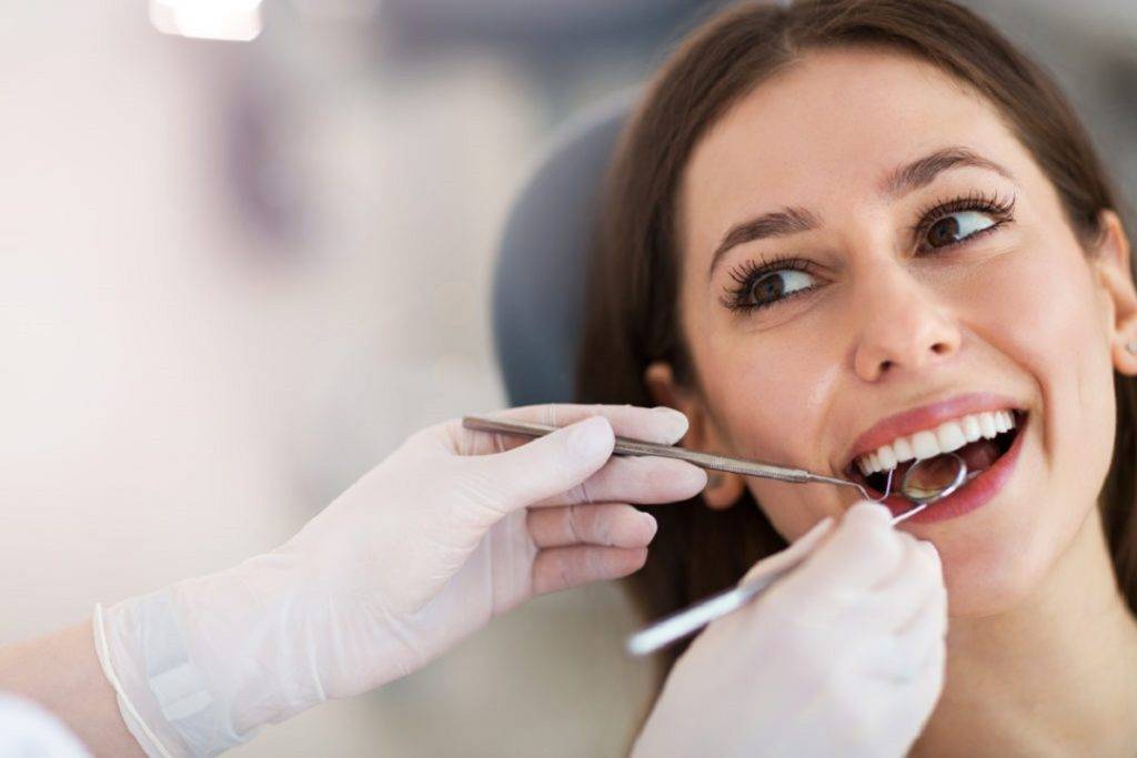 Dentist cleaning a patient’s teeth with dental instruments during a professional dental cleaning appointment.