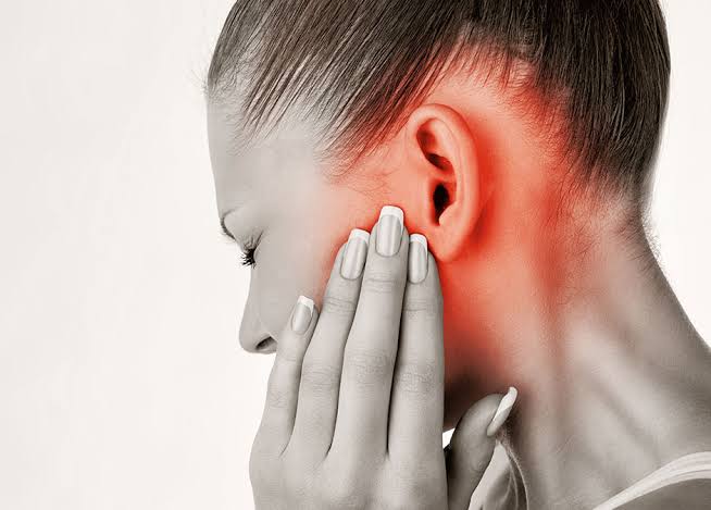 Person holding the area in front of the ear with a red highlight indicating pain around the ear and jaw.